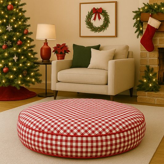 A red gingham round dog bed in a living room decorated for Christmas with a tree, stockings.